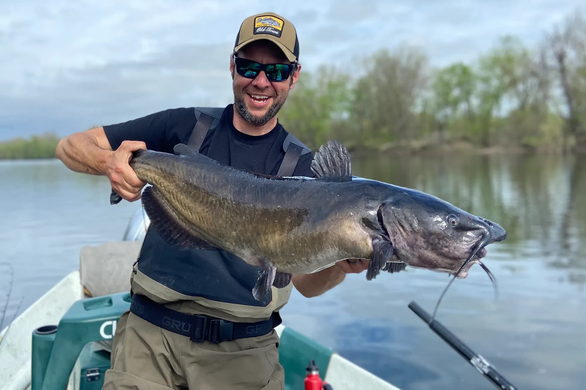 Angler on a boat holding up a large channel catfish